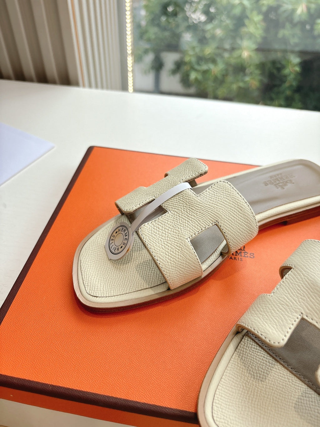 Hermes slide sandals in light beige with wide strap and circular logo charm