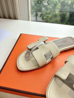 Hermes slide sandals in light beige with wide strap and circular logo charm