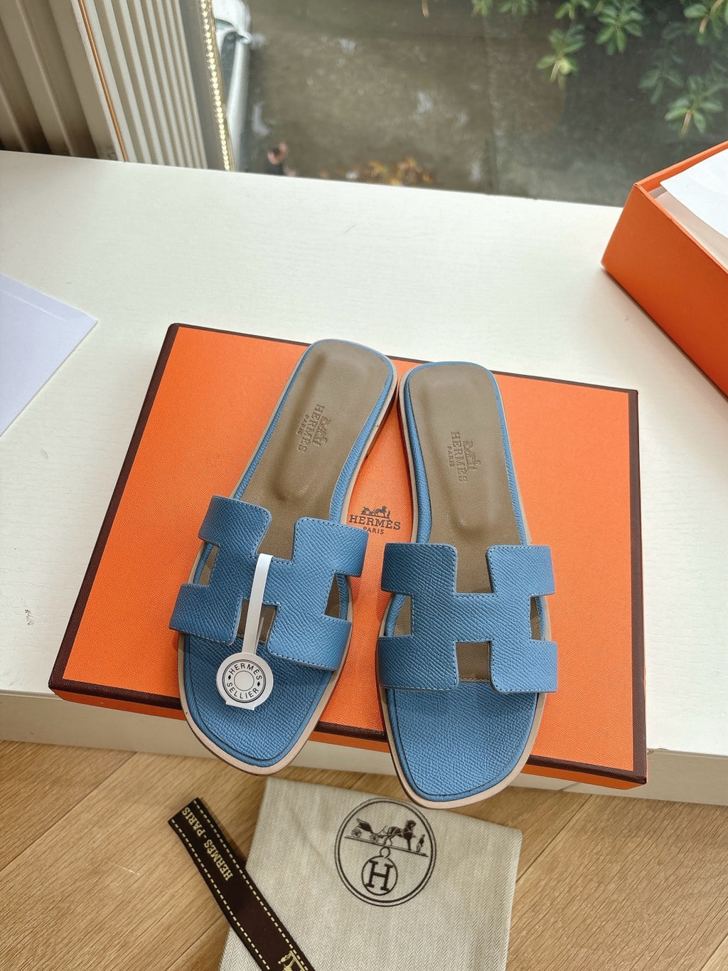 Blue Hermes slide sandals with H cutout and circular logo medallion on footbed