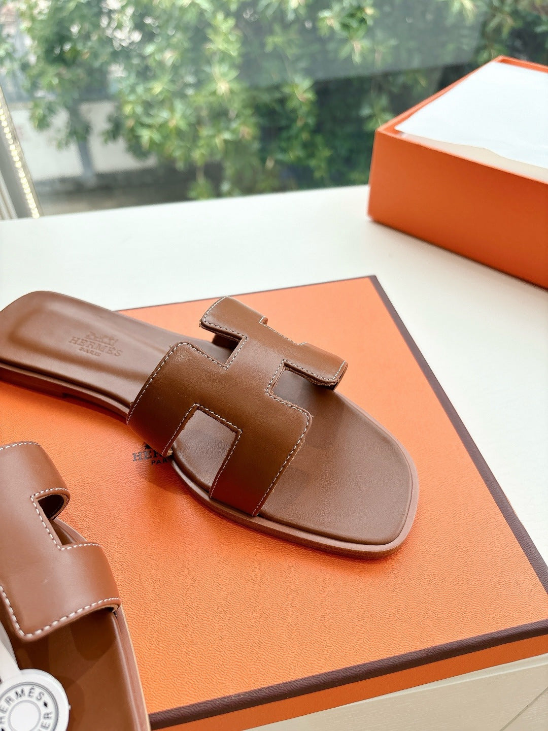 Hermes women's brown leather slide sandals, close-up of wide strap and logo