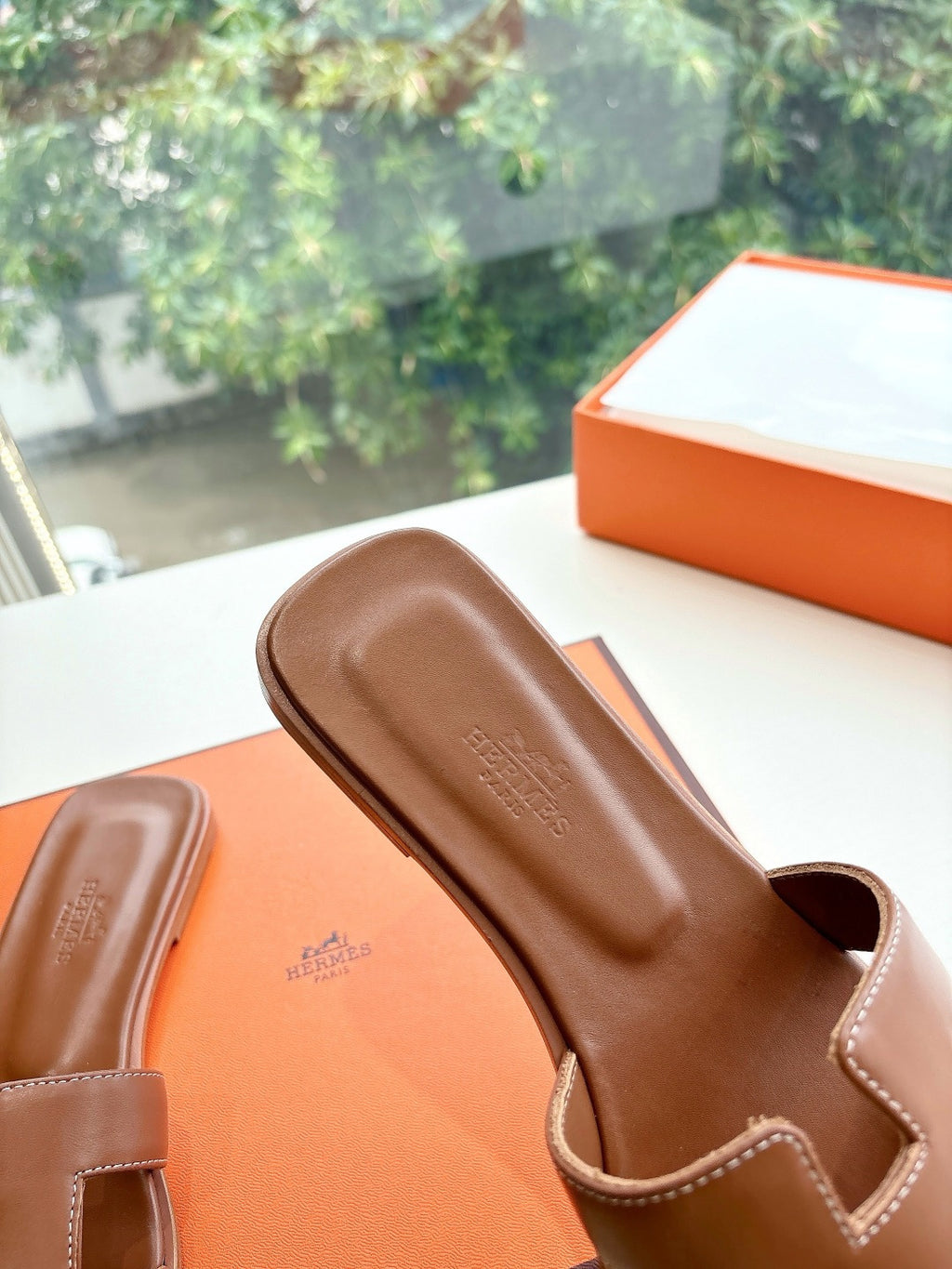 Hermes women's brown leather slide sandals, toe area close-up, embossed logo