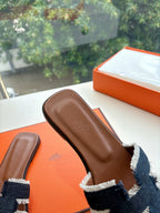 Hermes slide sandal close-up of brown footbed edge, with navy-and-light-blue woven strap