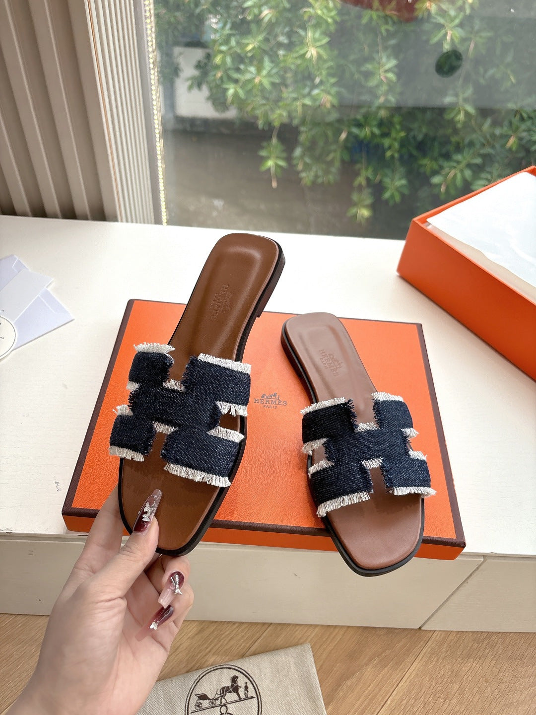 Hermes slide sandals worn shown side view, brown leather footbed with navy-and-light-blue woven strap