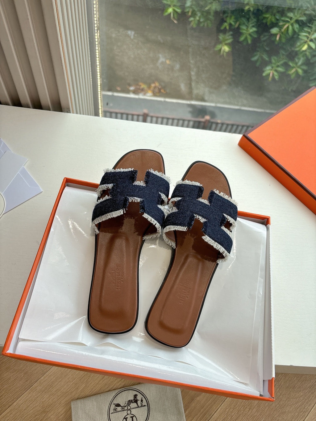 Hermes slide sandals showing two brown leather straps with dark navy and light blue woven detailing