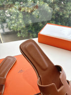 Hermes leather slide sandal side view, brown cushioned footbed