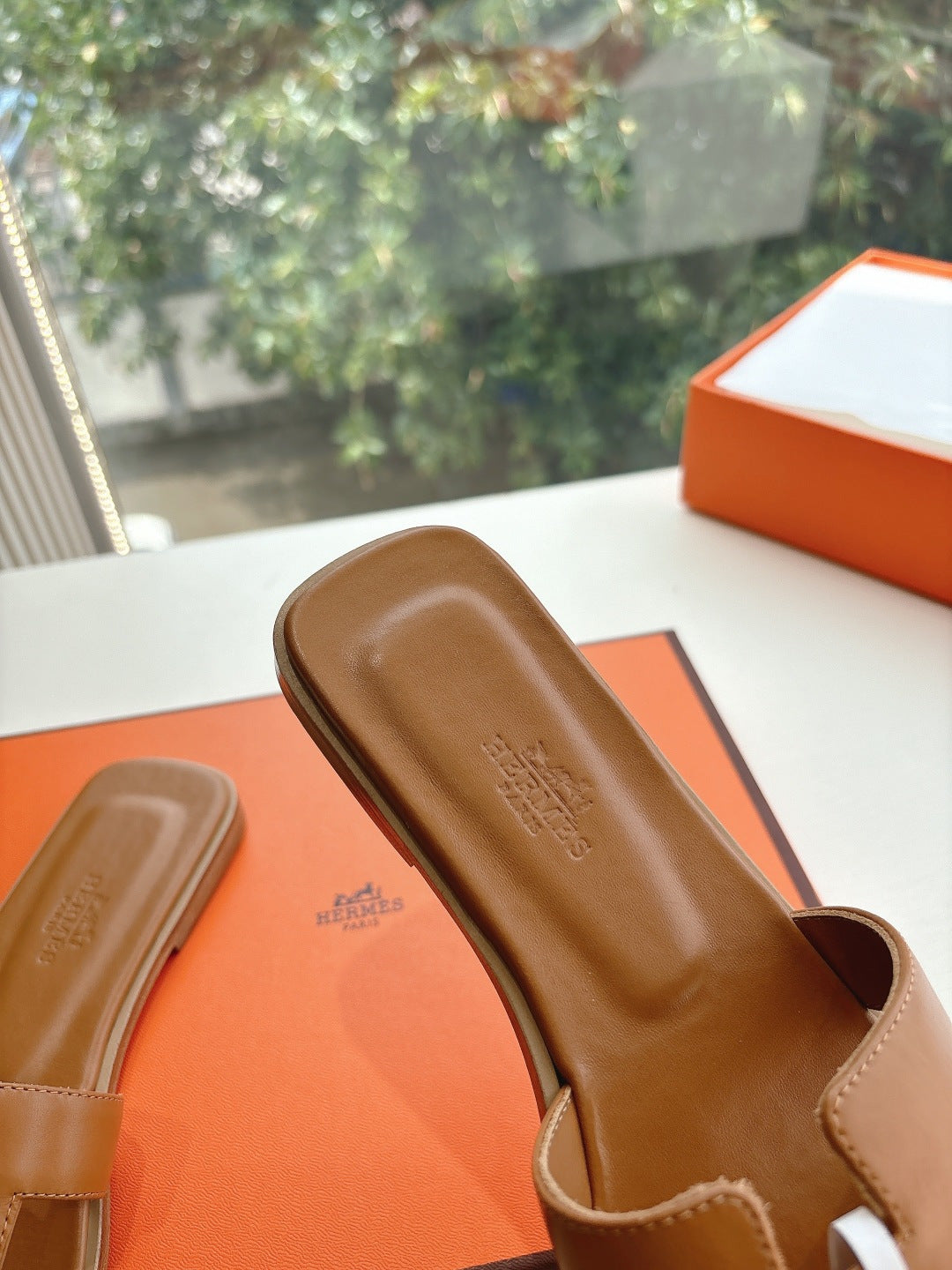 Hermes women's tan slide sandal close-up of footbed with stamped logo