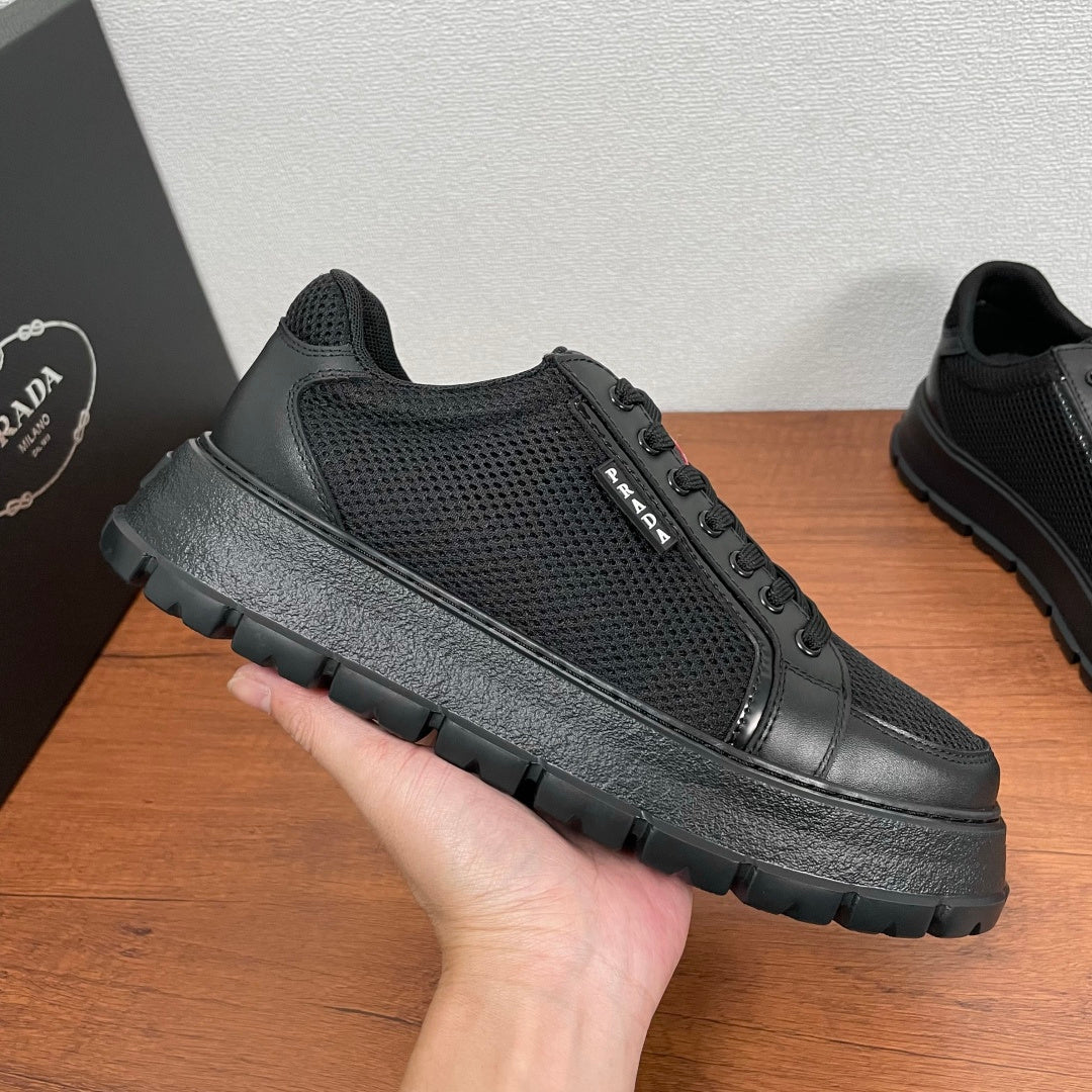 Black lace-up sneakers with textured mesh upper, leather toe, and chunky rubber sole