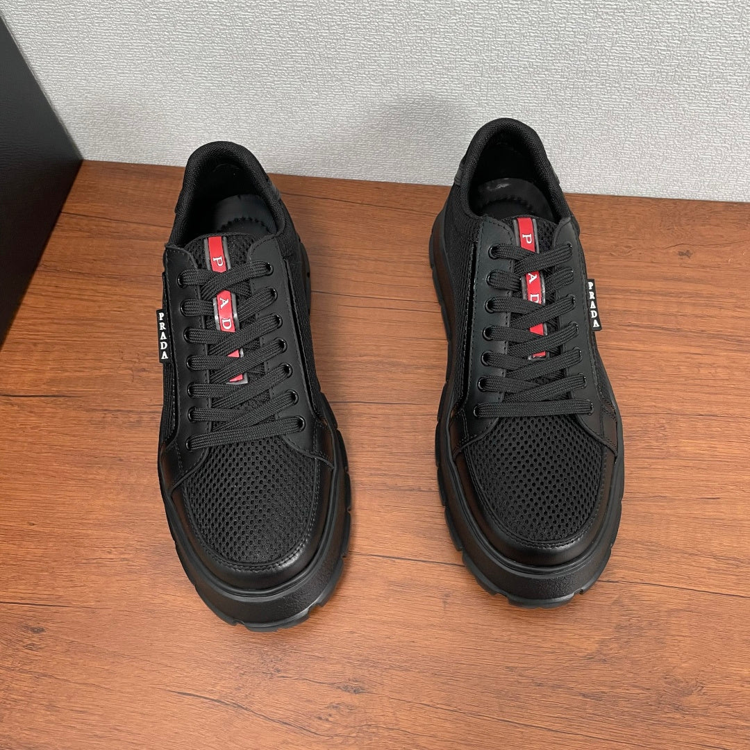Black lace-up sneakers, front view with chunky rubber sole and red PRADA logo accents