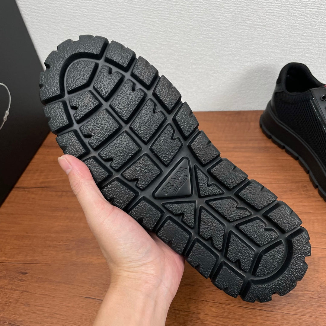 Black sneaker outsole with grid tread pattern and PRADA logo at center