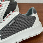 Prada unisex sneakers close-up side: gray perforated mesh, white leather trim, logo patch