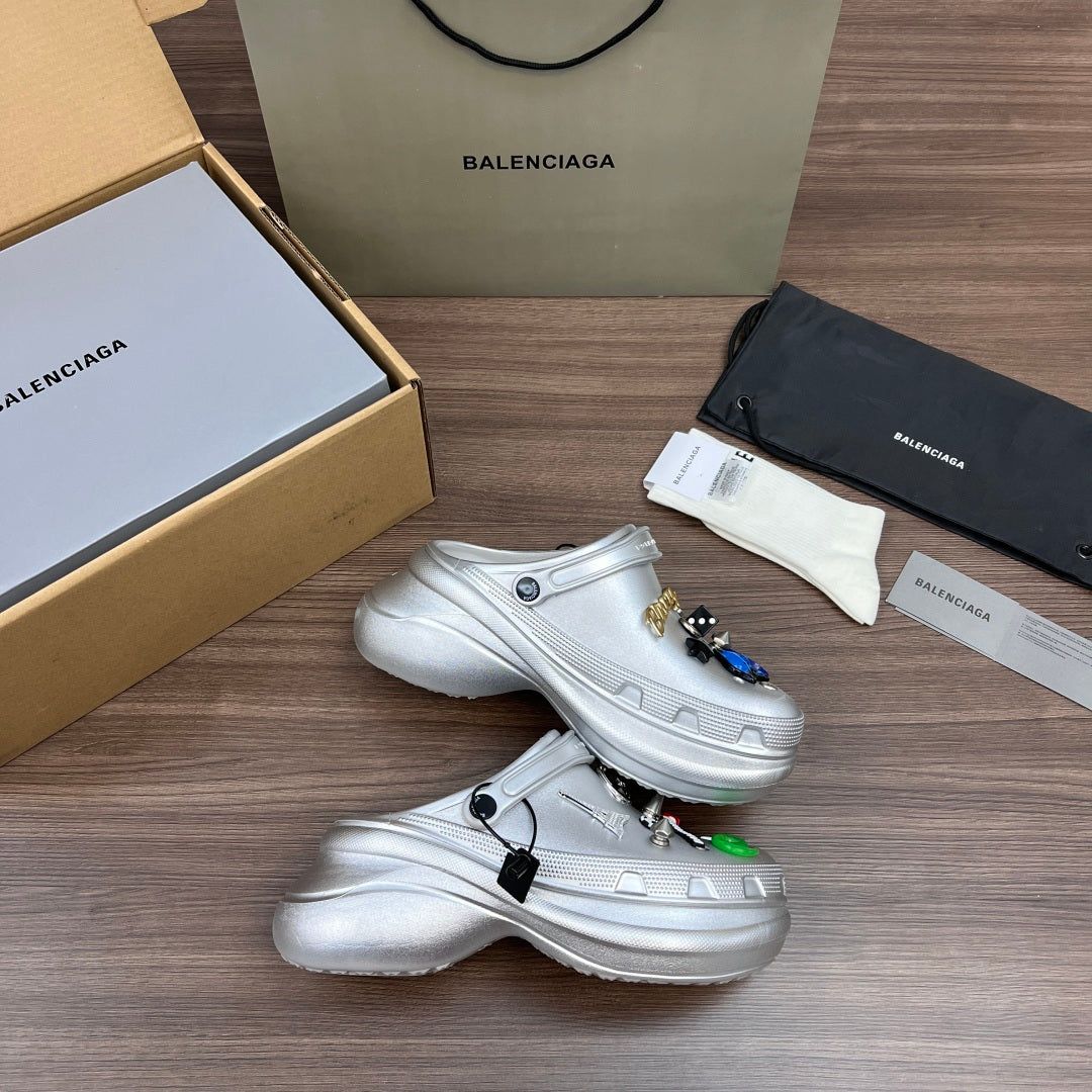 Silver clogs with vented toe, side strap, and metal charm accessories