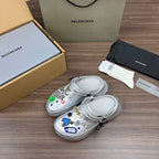 Silver clogs with vented toe, side strap, and colorful charm and badge accents