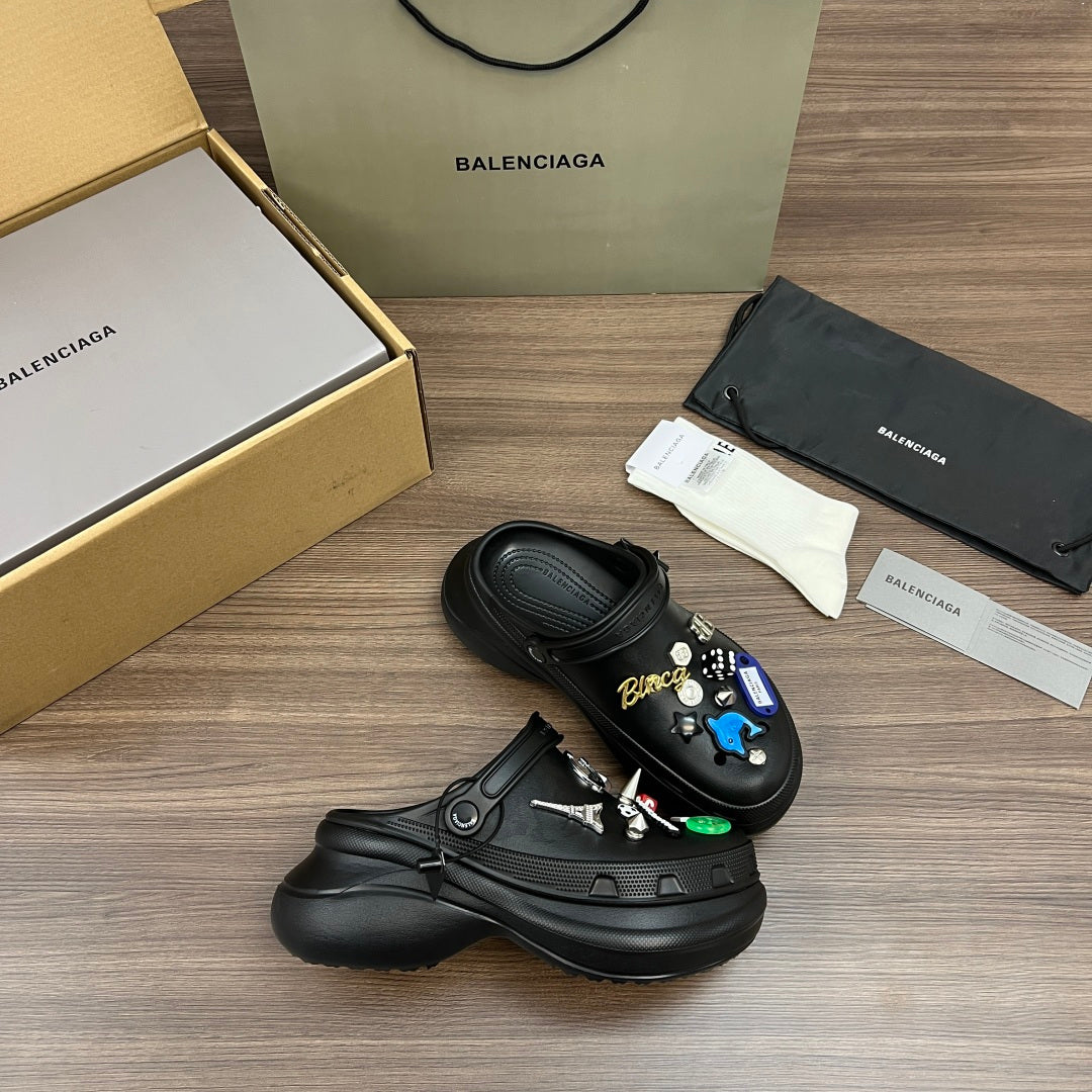 Black Balenciaga sandals with charms and lace tie, displayed with packaging items