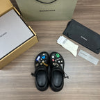 Pair of black Balenciaga sandals with lace ties and colorful charm embellishments
