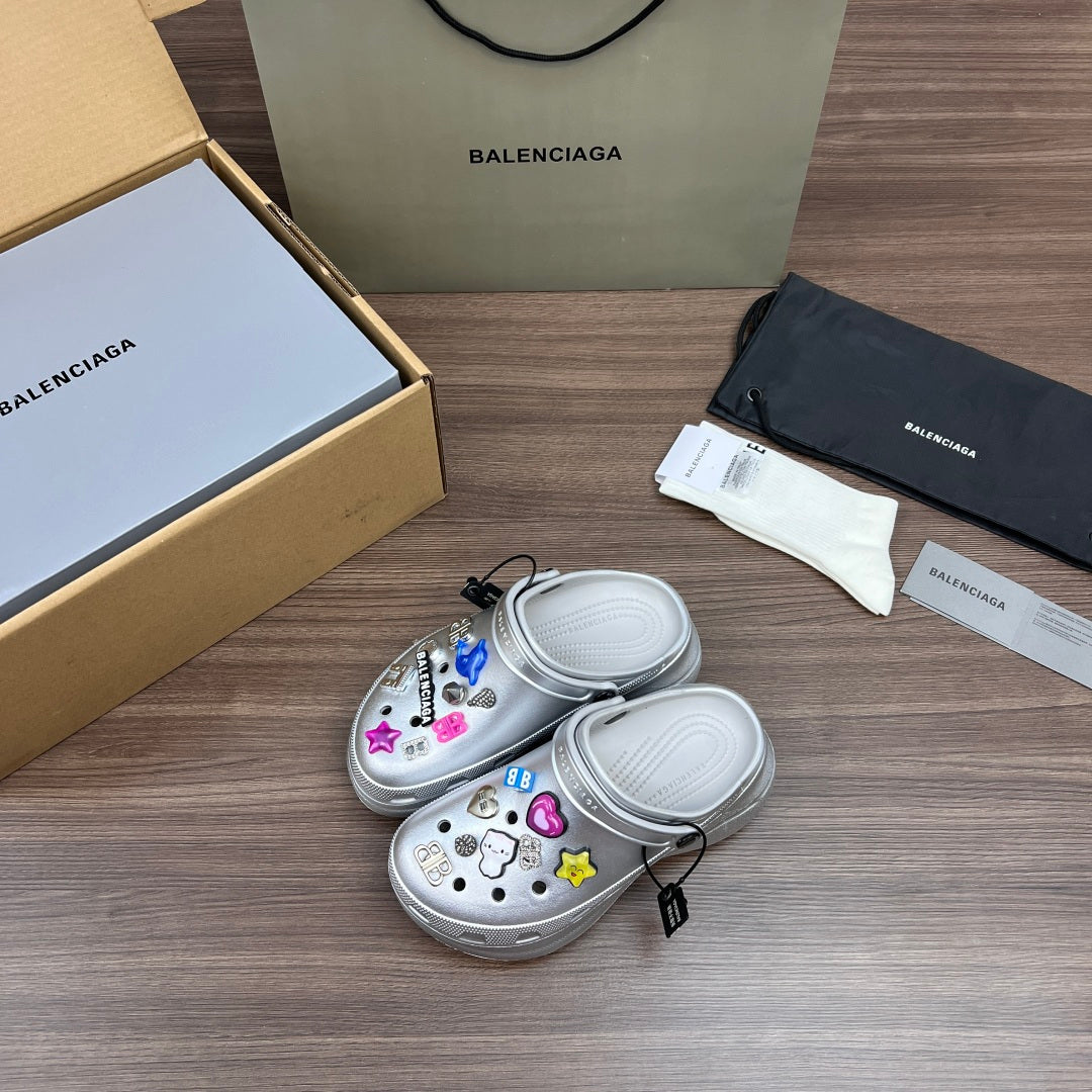 Balenciaga silver platform clogs, angled view, with colorful charm details