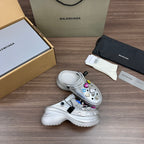 Balenciaga silver platform clogs, two-shoe view, with charm accessories