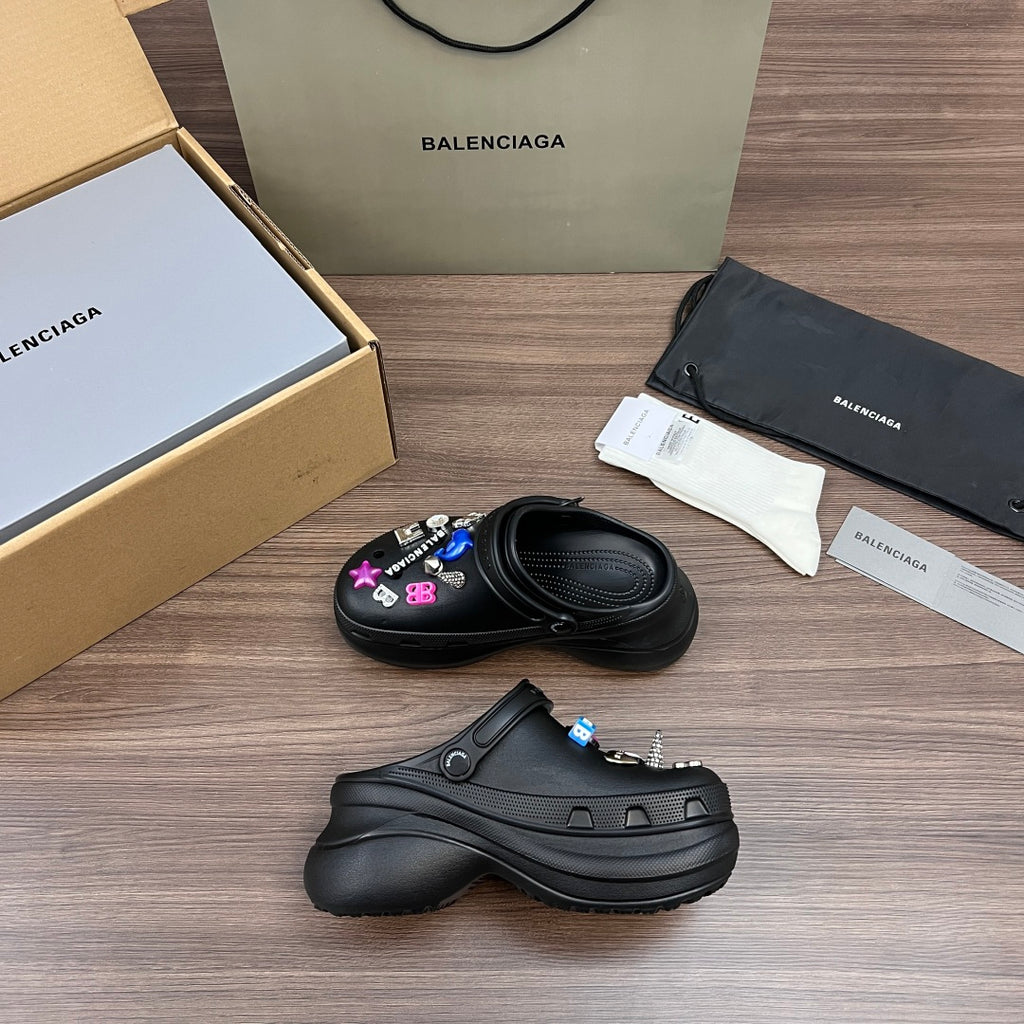 Black Balenciaga sandal clogs, one pair shown with decorative charm pins and straps
