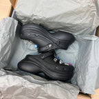 Black Balenciaga clogs in box with textured tread and small charm details