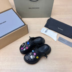 Black Balenciaga slide sandals with colorful charm patches, pair shown