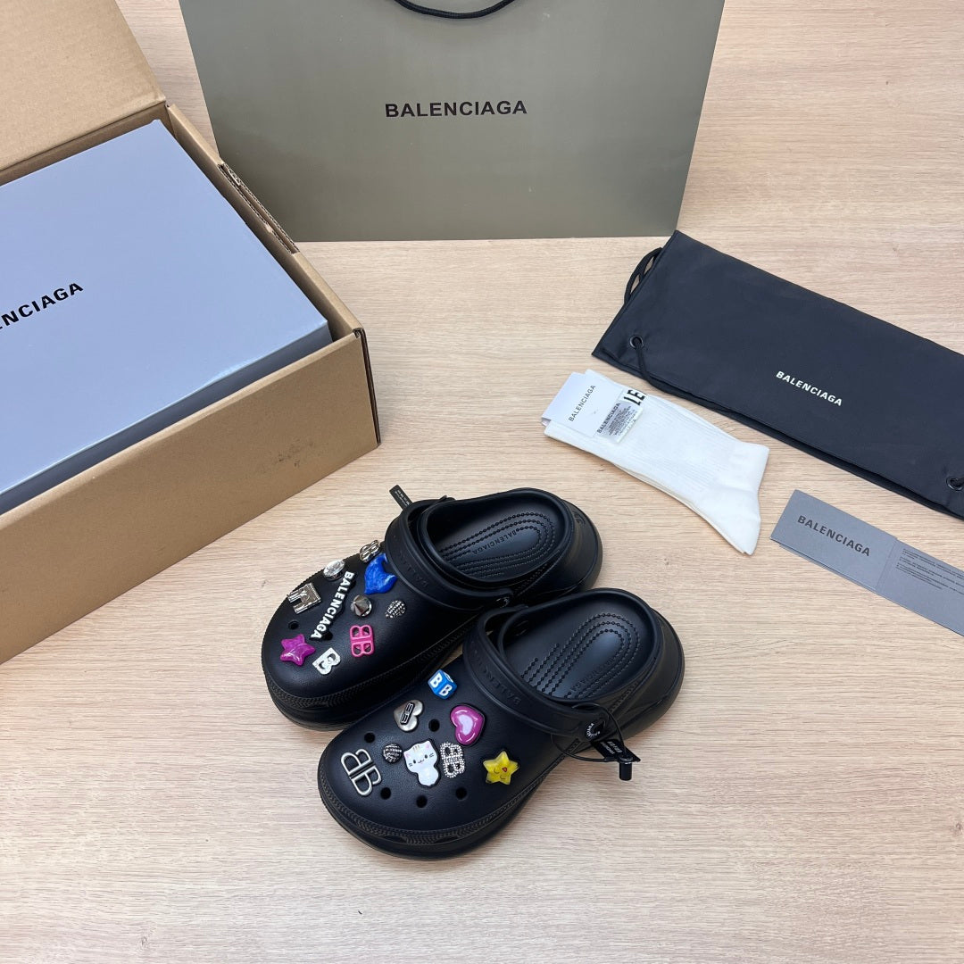 Black Balenciaga slide sandals with colorful charm patches, pair shown