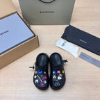 Black Balenciaga slide sandals with colorful charm patches, pair shown