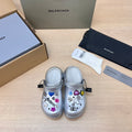 Silver slide clogs with open toe, ventilation holes, and colorful charm decorations