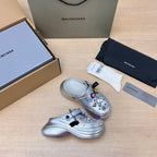 Silver slide clogs with open toe, ventilation holes, and colorful charm embellishments