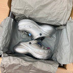 Silver slide clogs in box packaging, with open toe and side charm decorations