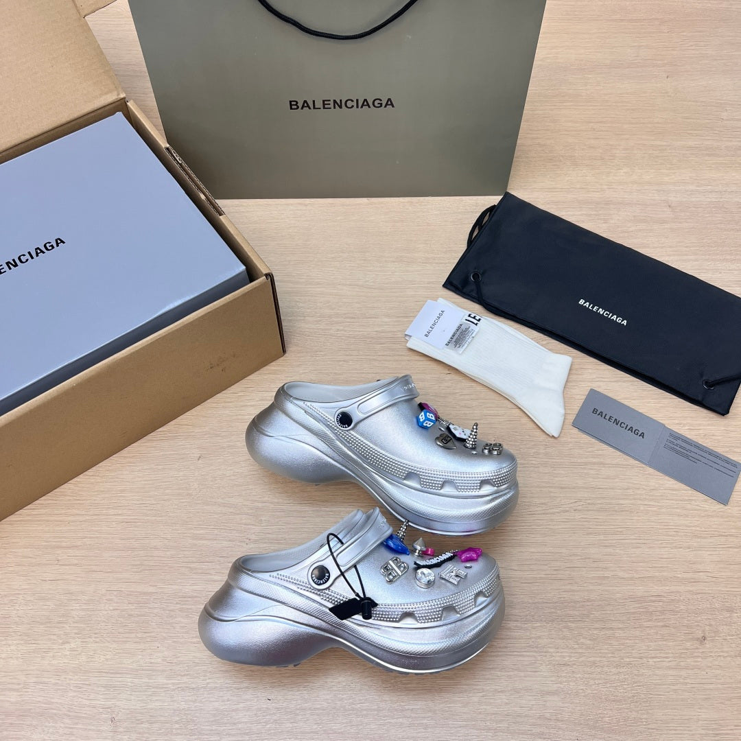 Silver clog pair with open toe, ventilation holes, and charm decorations on top