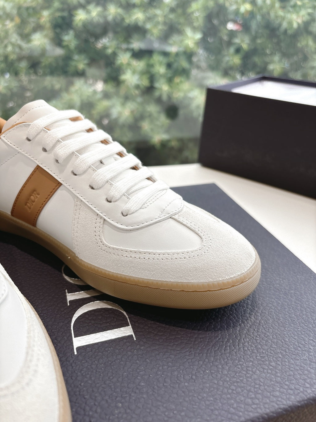 Close-up of white leather unisex sneaker with tan trim and lace-up