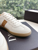 Close-up of white leather unisex sneaker with tan trim and lace-up