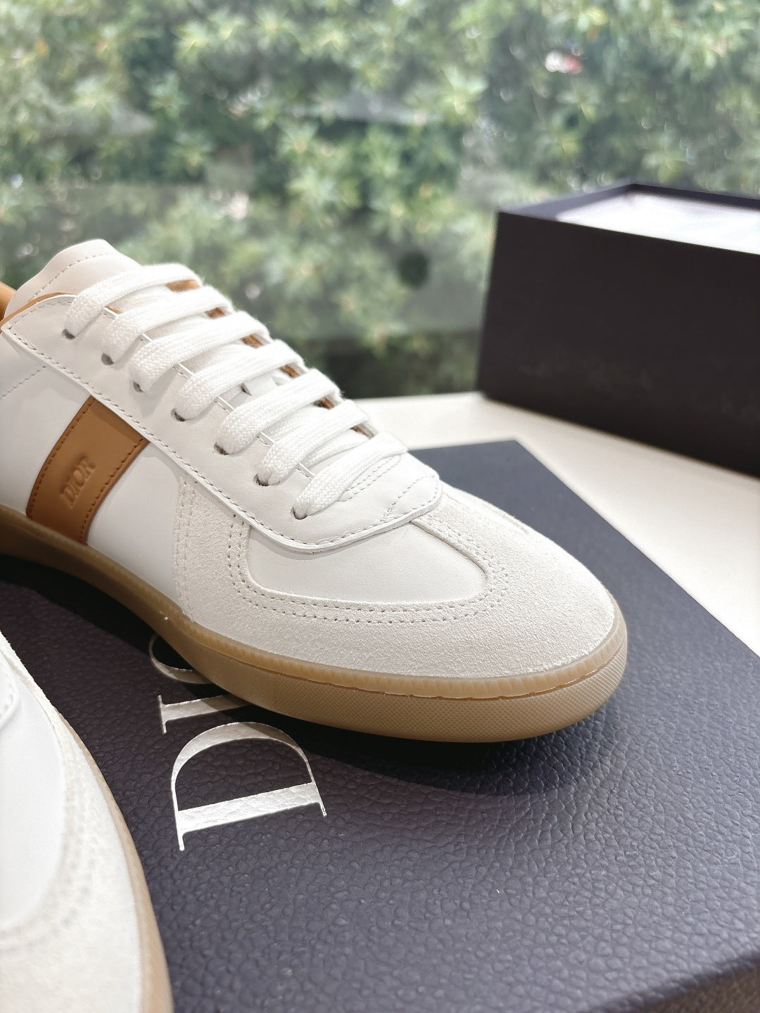 Close-up of white leather unisex sneaker with tan trim and lace-up