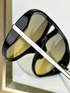 Black sunglasses with gold-tone bar and “Bottega Veneta” branding detail
