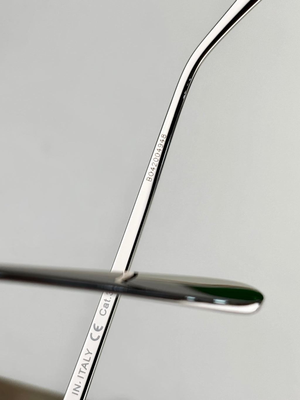 Sunglasses arm close-up with “ITALY” and part numbers printed on the metal