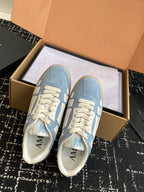 Light blue sneakers with white laces and AMIRI logo on the heel