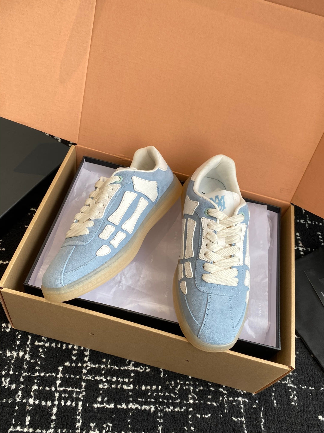 Light blue low-top sneakers with white laces and white graphic side stripes
