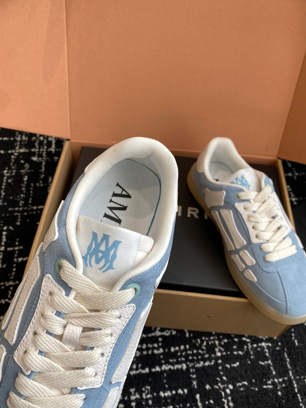 Light blue sneakers with white interior lining and AMIRI branding on insole