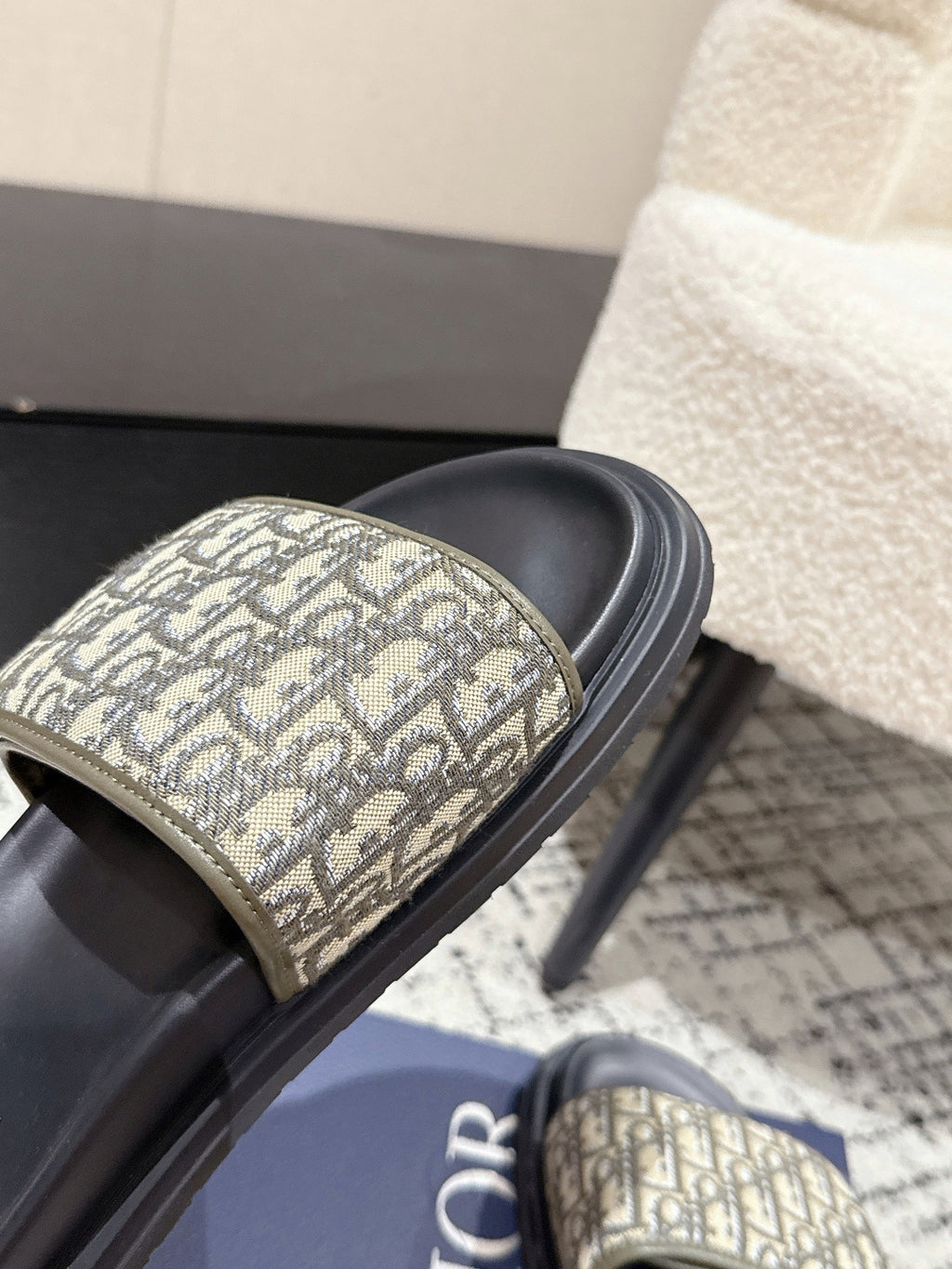 Close-up Dior slide strap with beige Dior Oblique pattern and black cushioned sole