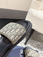 Close-up Dior slide strap with beige Dior Oblique pattern and black cushioned sole