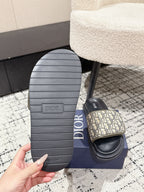 Dior slide sandal outsole view with ribbed gray sole and beige logo strap