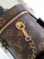 Louis Vuitton monogram bag close-up with gold zipper pull and attached chain strap.