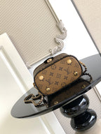 Louis Vuitton monogram mini bag with gold buttons, chain strap, and top zipper opening.