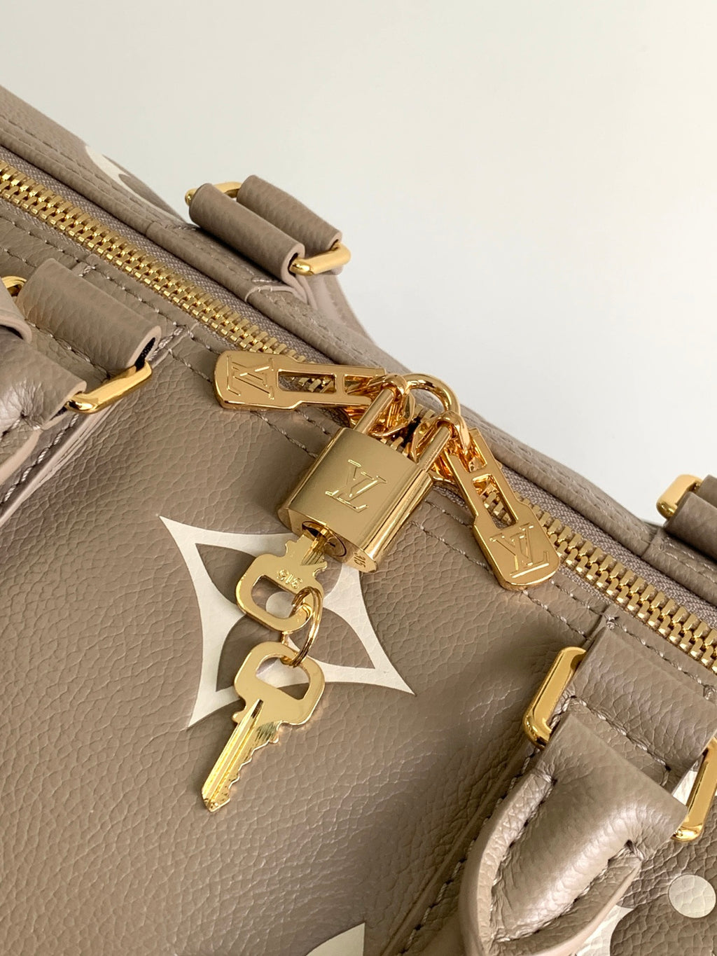 Louis Vuitton bag close-up: taupe leather, gold zipper pull and charm keyfob