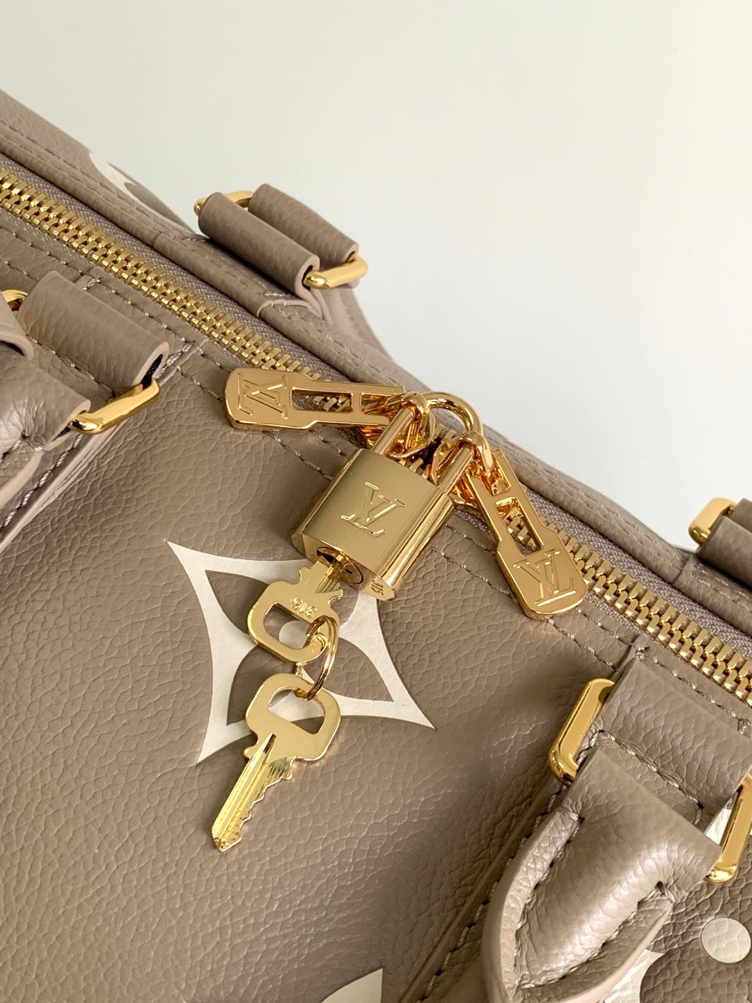 Louis Vuitton bag close-up: taupe leather, gold zipper pull and charm keyfob