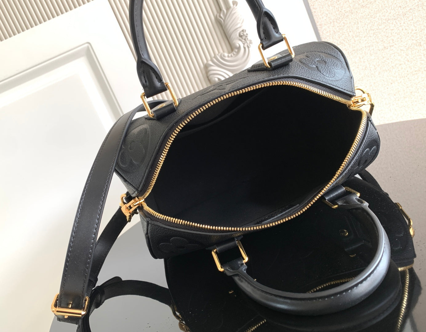 Louis Vuitton bag open view with black interior and gold-tone zipper along top edge