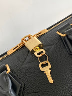 Louis Vuitton bag close-up of gold zipper pull and key-shaped charm on textured leather
