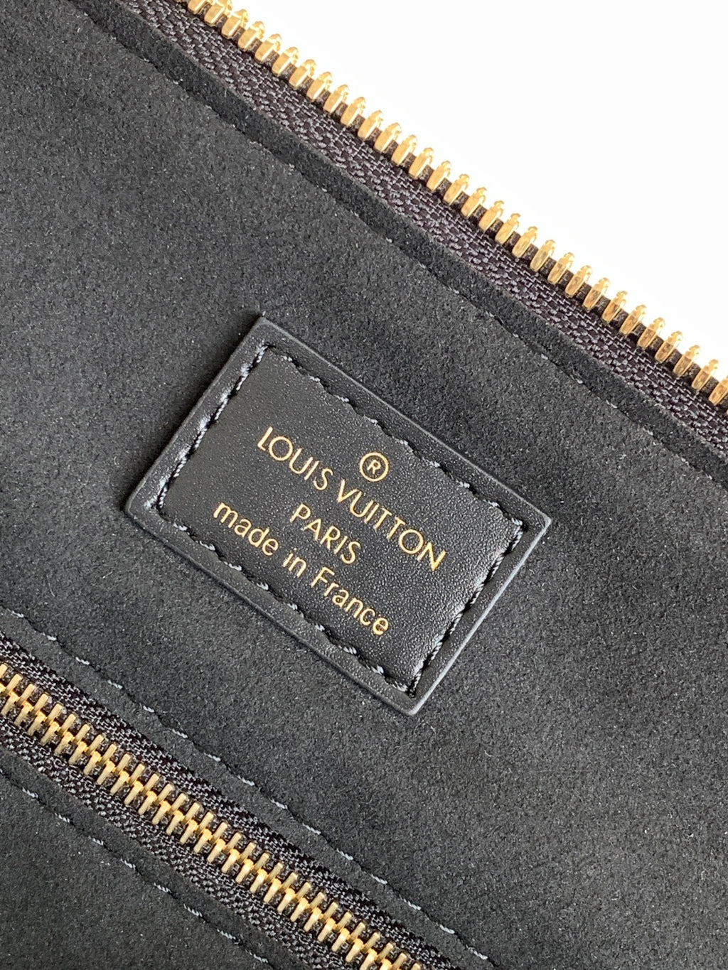 Louis Vuitton made in France label on dark leather with gold zipper stitching