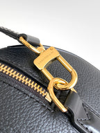 Louis Vuitton bag close-up of gold clasp and zip track on dark leather