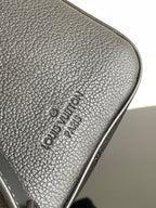 Louis Vuitton logo embossed on textured dark leather trim at bag corner