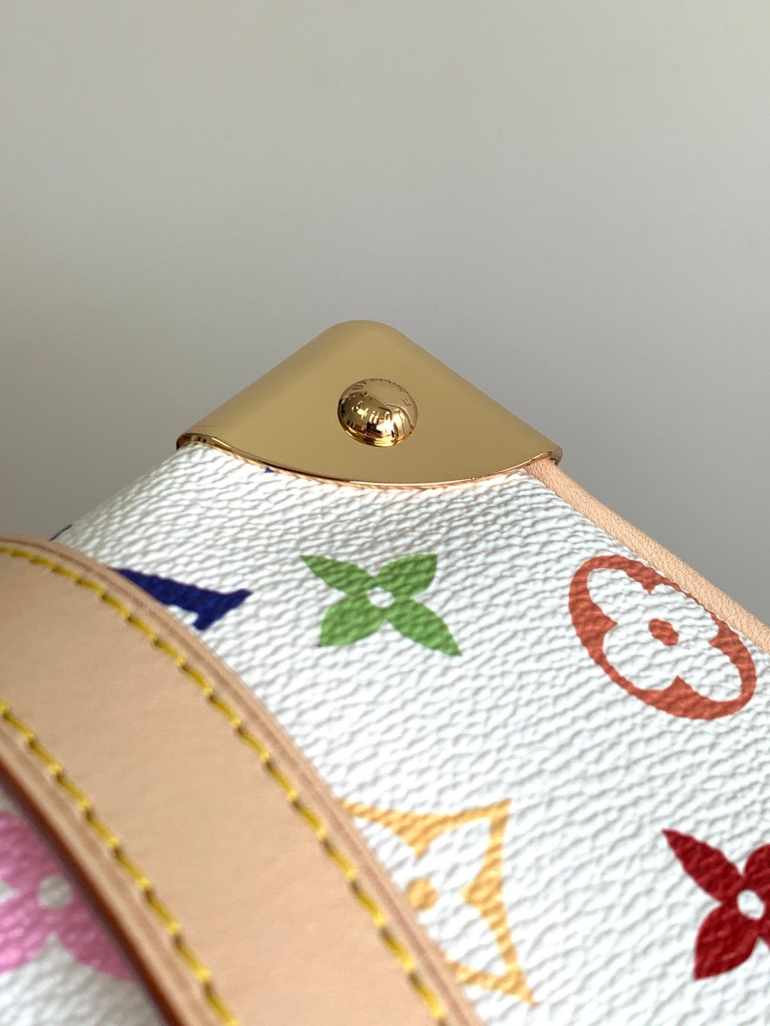 Louis Vuitton monogram handbag close-up of gold top button on multicolor canvas